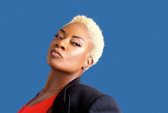 A headshot of Jully Black, posing for the camera in front of a blue background.
