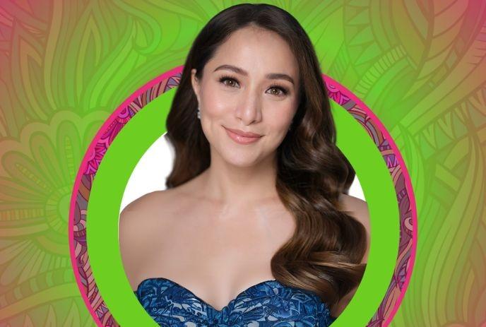 A woman in a blue strapless dress with long wavy hair, framed by a colorful green and pink circular background.