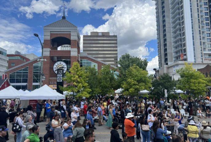 A large crowd of people at a previous island fest outside of Covent Garden Market on a sunny day.