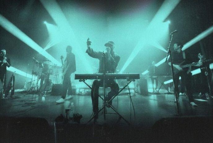 Wing Night performs energetically on stage with glowing lights in the background.