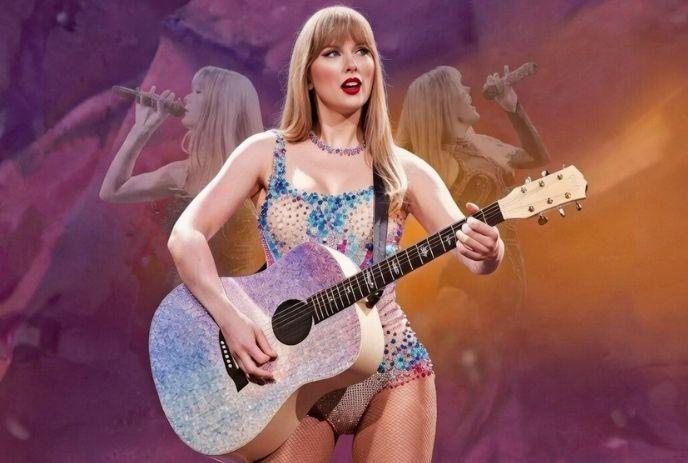 A woman with long blonde hair in a sequined outfit plays a purple guitar on stage.