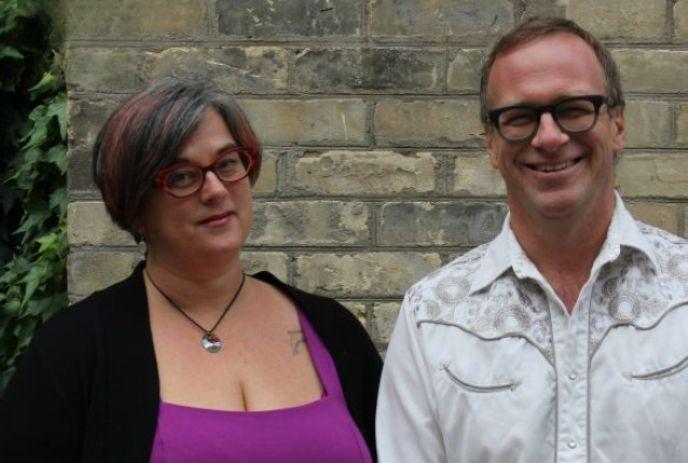 Amanda Lynn Stubley in red glasses and purple top with a black cardigan stands next to Martin Horak in glasses and a white shirt.