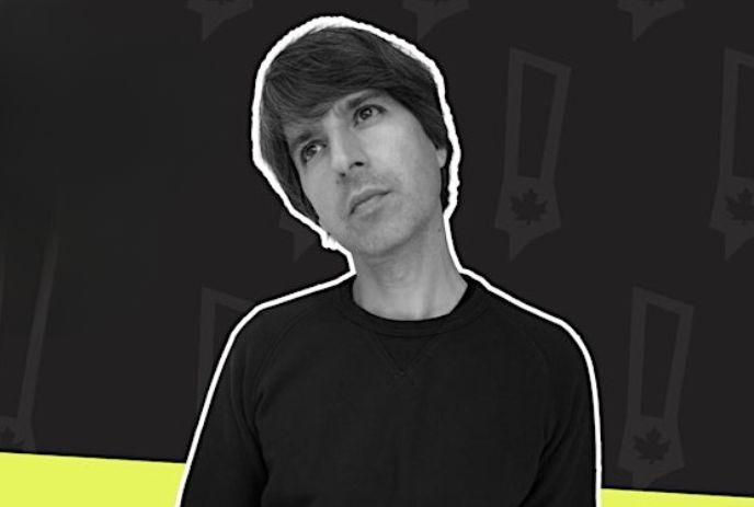 Demetri Martin wearing a long sleeve black shirt, looking up at the sky.