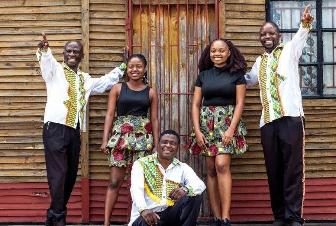 5 band members of Black Umfolosi posing outside in front of a wooden house.