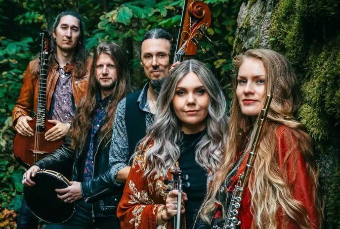The folk band FRÄNDER posing outdoors in a mossy forest.