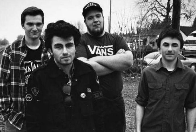 A black and white photo of the 4 band members of No Exceptions, posing together outside.