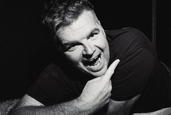 A black and white photo of Ian Bagg, posing for the camera, smiling.