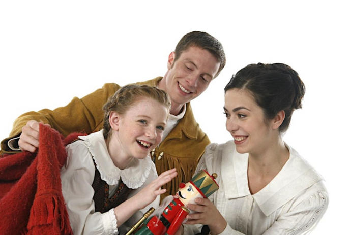 Two adults giving a child a gift of a red nutcracker doll.