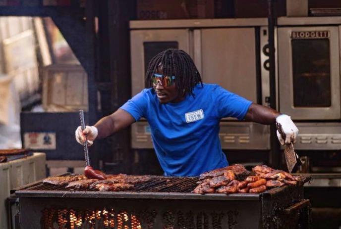 A person in a blue shirt and glasses grilling the fresh ribs on the griller.