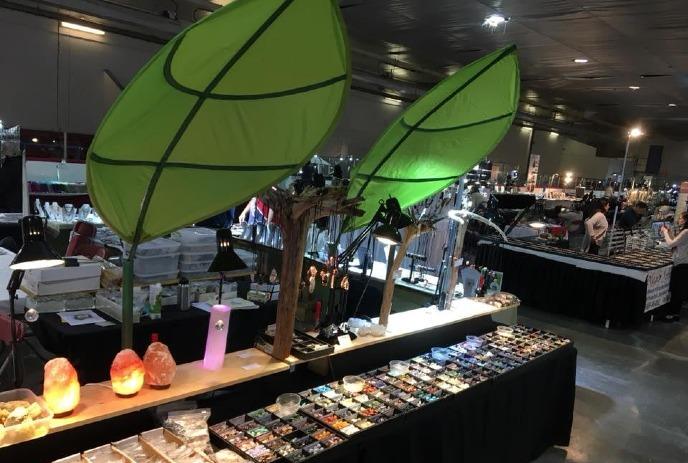 A vibrant market stall with green leaf decorations, colorful gemstones, and Himalayan salt lamps on display.