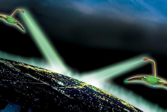 Two flying saucers hover above night city, casting bright green beams over glowing urban lights.