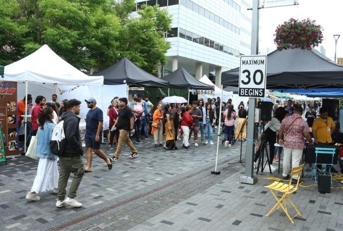 A group of people walking and checking vendor booths in the market lane.