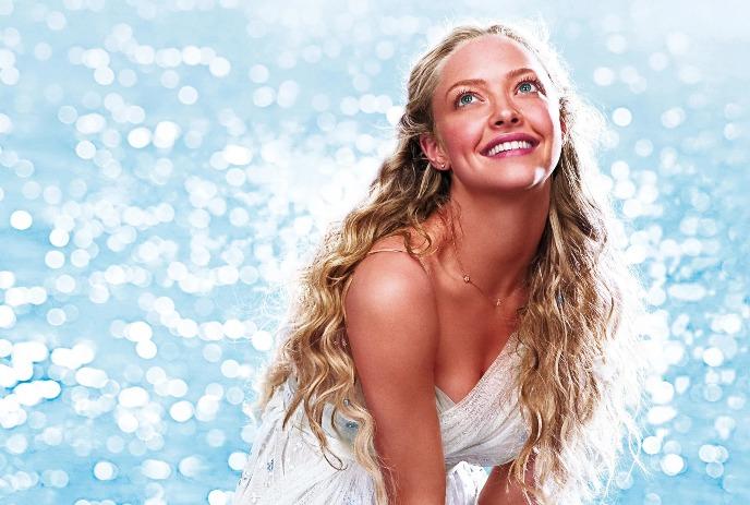 Women in white dress before bright shimmering backdrop gazing upwards.