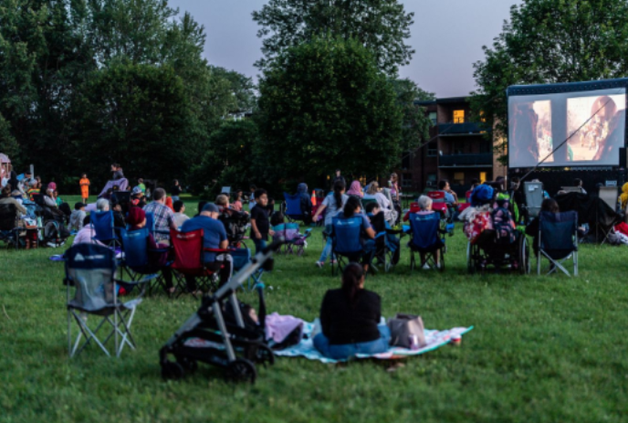 People set up in the park in front of a movie screen.