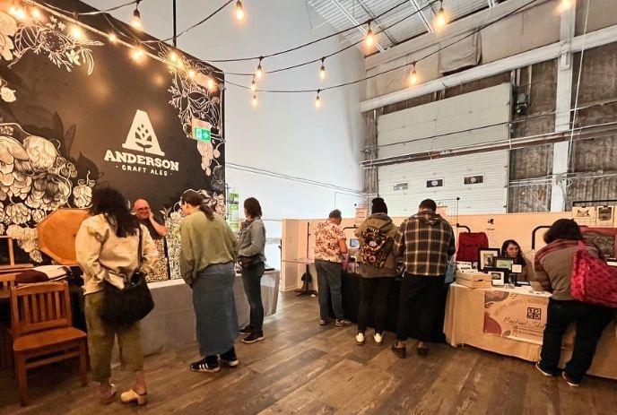 People gather around different booths at Anderson Craft Ales to look at items for sale.