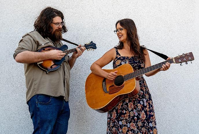 Allison Brown & Dan Henshall playing mandolin and guitar against white wall creating casual duet moment together