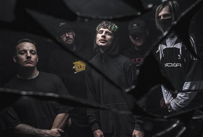 5 band members of Alpha Wolf stand in dark clothing, viewed through shattered glass.