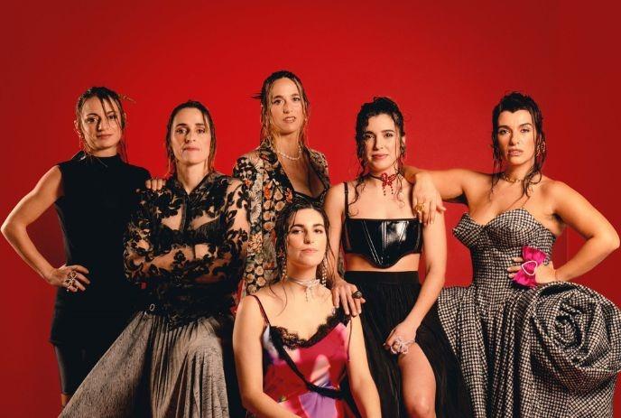 Six artists from Maruja Limon posing for a picture under the red background.