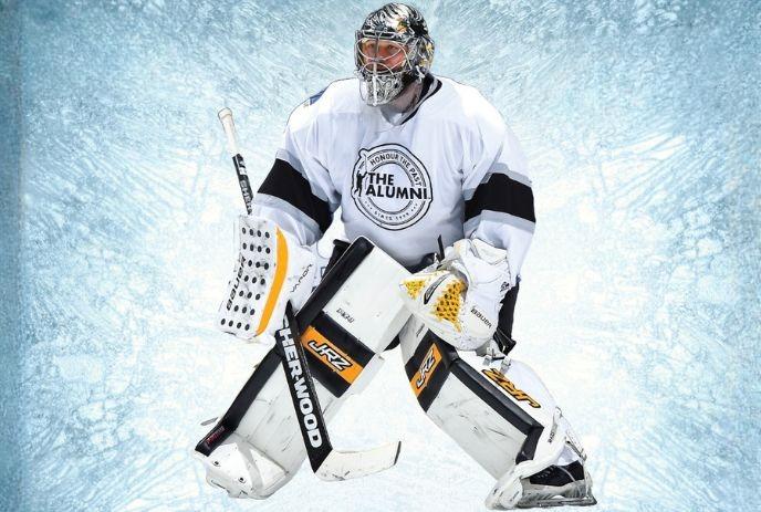 Hockey goalie in full gear standing under a frozen blue background.