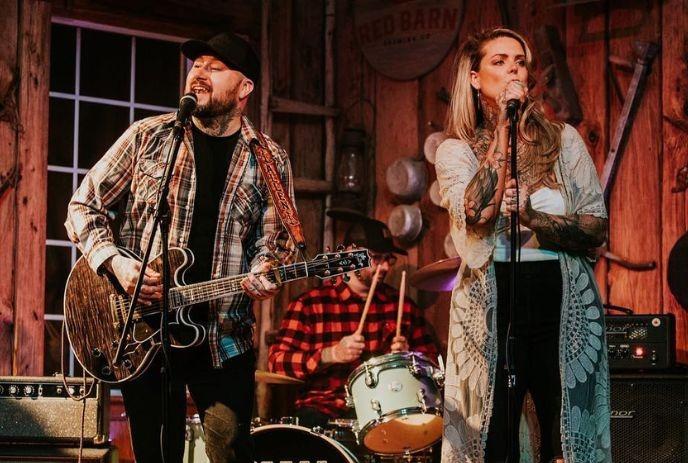 Three musicians performing with a cozy warm brown background.