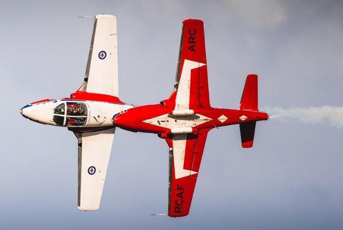 Two jets, red and white flying with wings nearly touching at an aerial display.