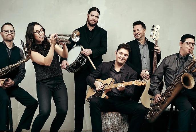 The 6 members of the André Bisson Band, posing with their instruments for the camera in a blank room, wearing formal attire.