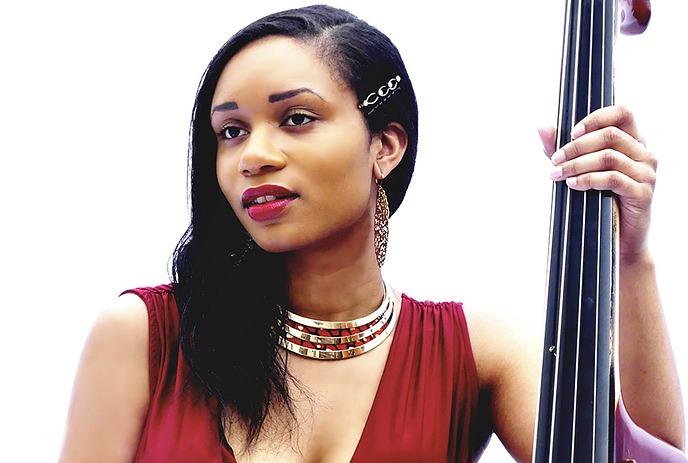 Angelique Francis wearing a red dress, holding a cello against a white background.