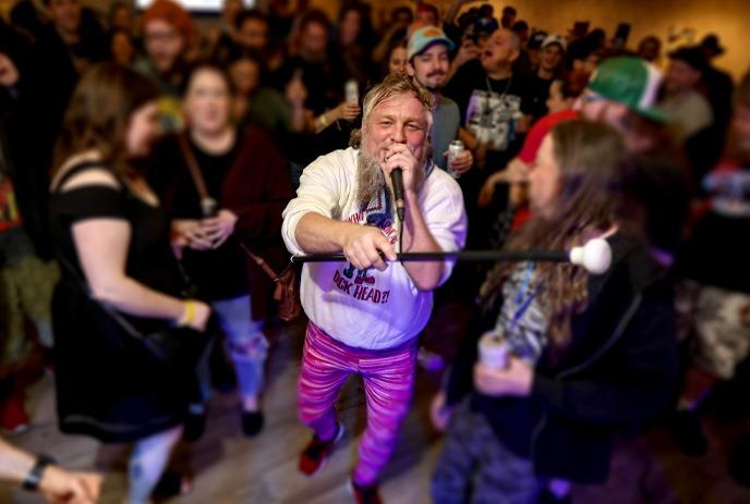 One person holding a microphone to another in front of a group of people at the Shock Stock Horror Film Festival.