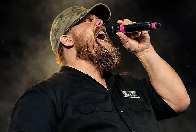 A person wearing a hat singing into a microphone.