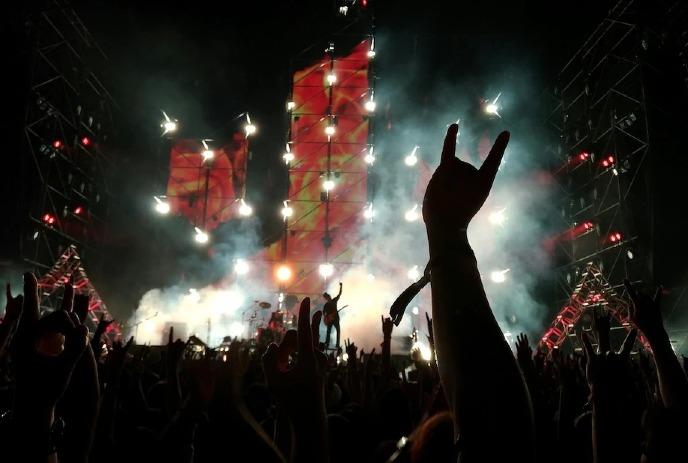 Classic Albums Live performs on stage with dramatic lighting, as the crowd raises their hands.