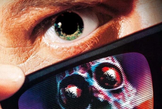 A person lifts sunglasses to reveal a hidden skeletal face reflected sharply in the lens.