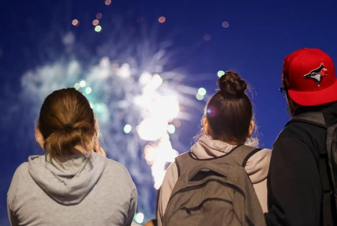 Red-hued image of people sitting together watching fireworks.