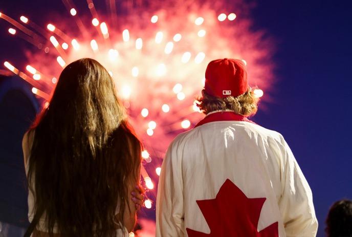 Red-hued image of people sitting together watching fireworks.