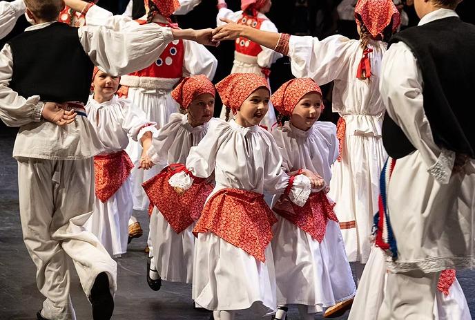 Young people in traditional red and white dress dancing in between older people.