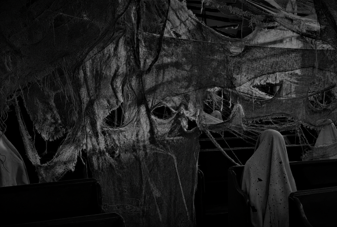 Dark haunted display with tattered hanging fabric and ghost figures inside a dim room.