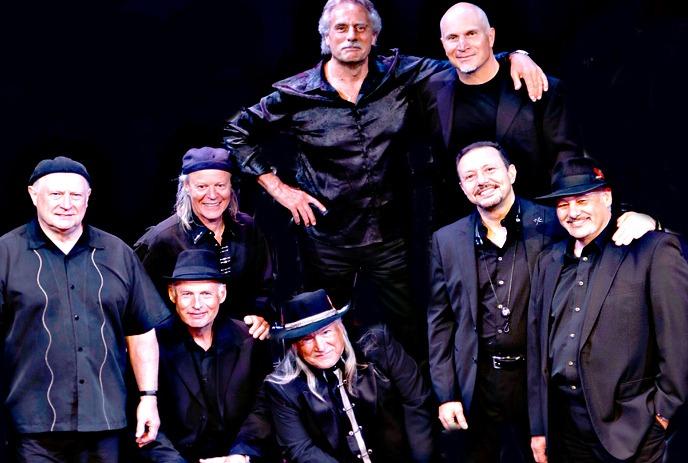 Eight group members wearing black, posing for a  photograph.