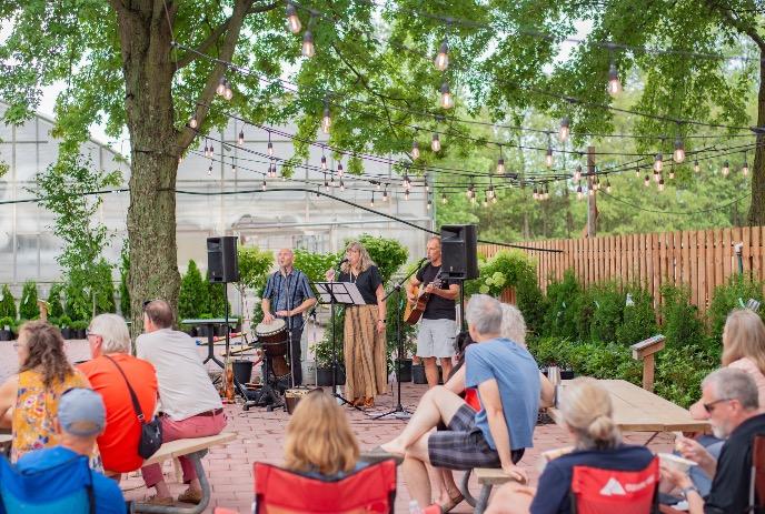 An evening at Cider Gardens, Heeman's Farm in London, Ontario, with live music as guests relax beneath trees and lights.