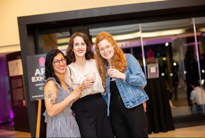 3 people smiling together and holding drinks