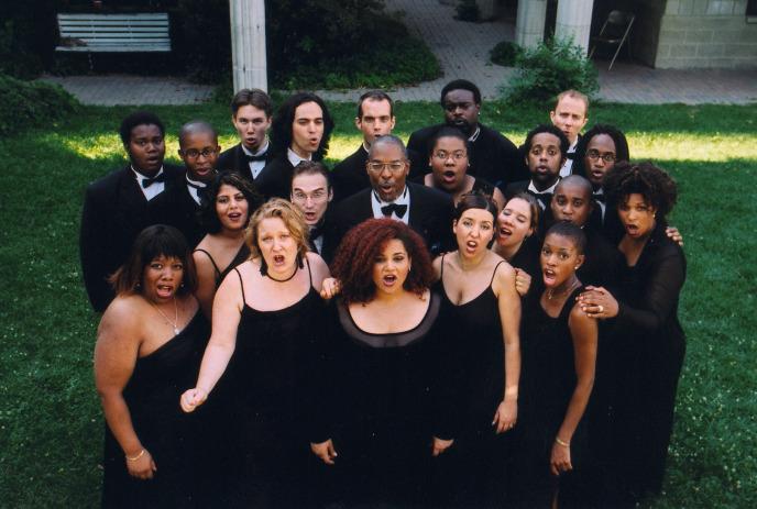 Large group of people singing together outside of a building.
