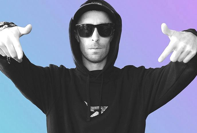 DIRTYSNATCHA in black and white, wearing sunglasses and a hoodie, posing with hands pointed outward.