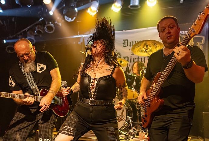 Down 'N' Dirty performs on stage with vibrant green-blue lights; vocalist leads guitar, bass, drums.