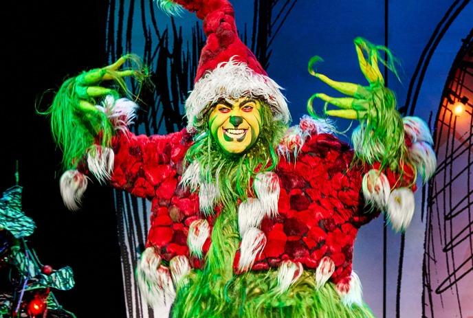 A festive Grinch in a red and white Santa outfit, paired with fuzzy green pants.