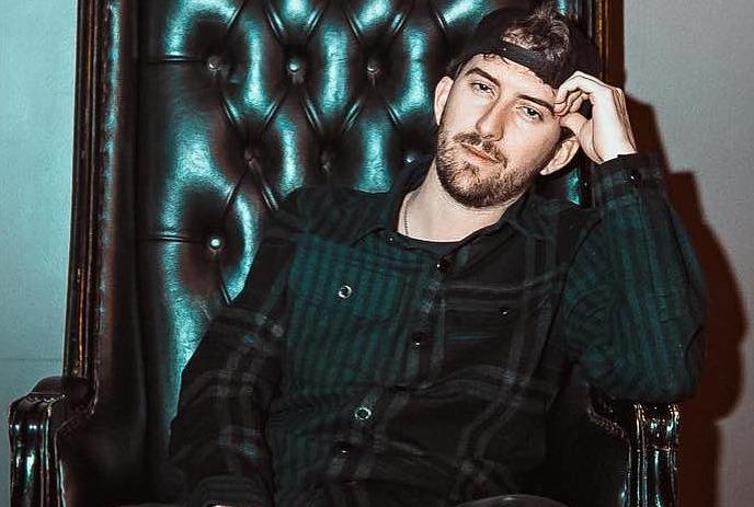 EDM producer and DJ, DREZO, sitting on a leather chair