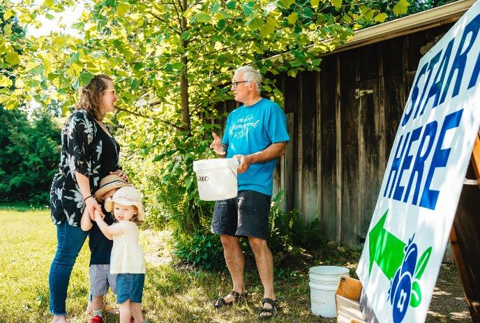 Four people standing in front of a sign for blueberries.