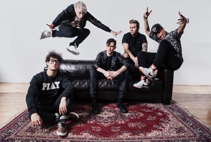 The band Down With Webster posing dynamically with jumps and sits around a black couch on a red rug.