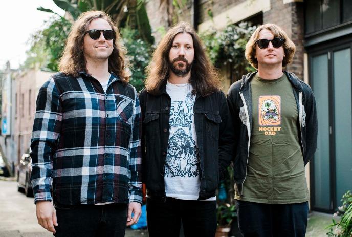 The three band members of DZ Deathrays posing together on a street outside.