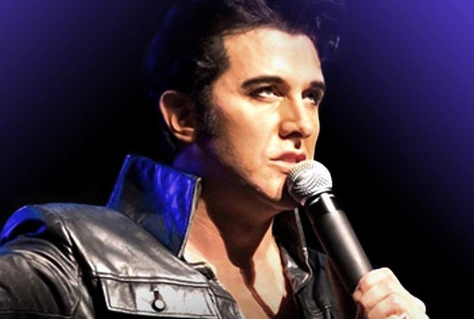 Elvis holding a microphone wears a black leather jacket, performing under a dark background with styled hair.