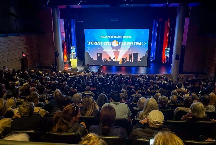 A crowded theater watches a presentation at the Forest City Film Festival.
