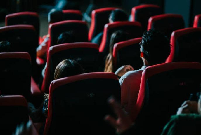 A large group of people in a movie theatre watching a film