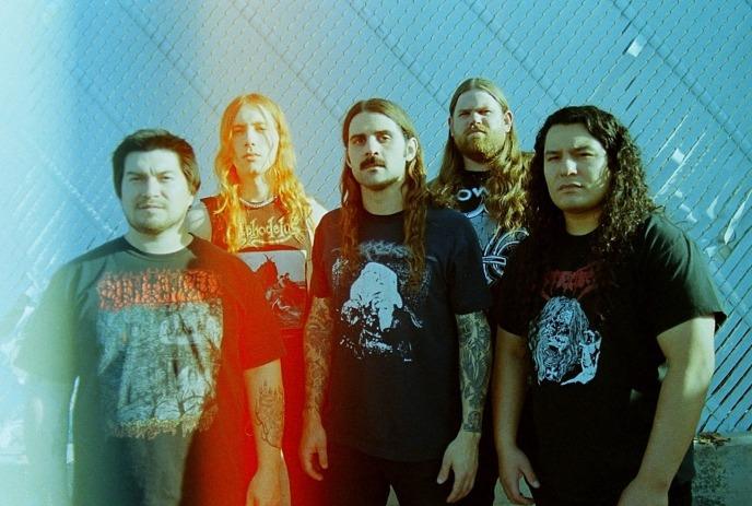 The 5 band members of Gatecreeper standing together, posing for a photo outside.